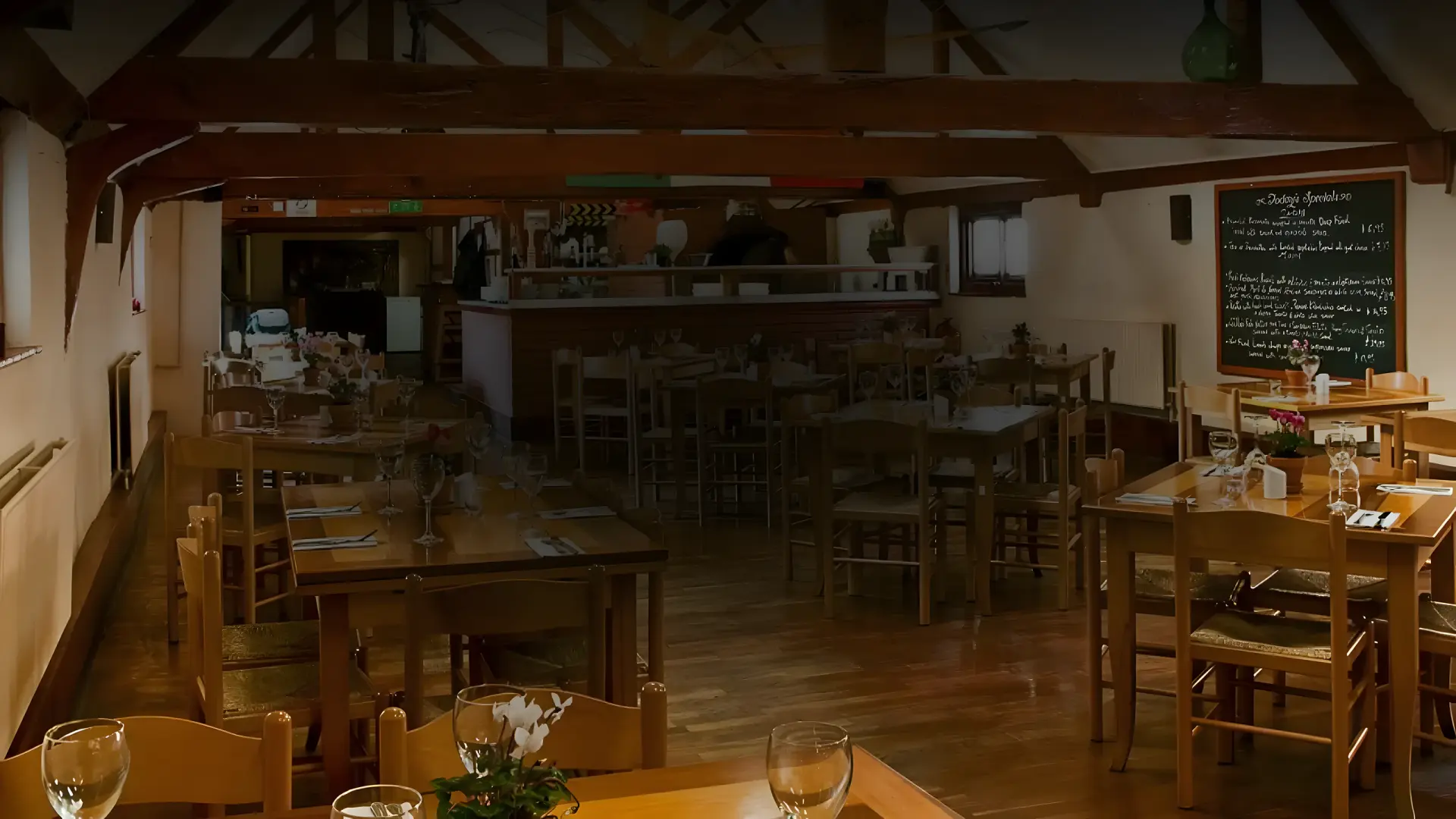 The beamed dining room at Luigi’s, with wooden tables and chairs laid for service