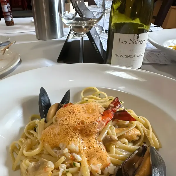 Linguine with mussels and prawns, with a bottle of Sauvignon Blanc behind